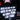 Person wearing a black jacket with text about music genres in a dark setting