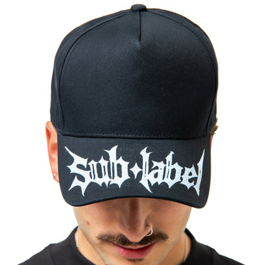 Person wearing a black cap with 'Sub Label' logo on a white background