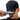 Person wearing a black cap with white text, adjusting it on a white background
