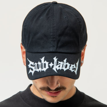Person wearing a black cap with 'Sub Label' logo on a white background