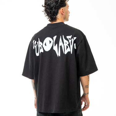 Person wearing a black t-shirt with white text on the back, standing against a white background