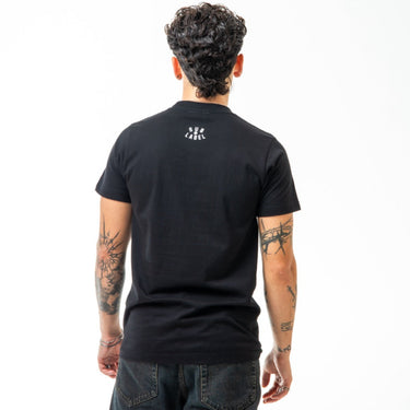 Person wearing a black t-shirt with a logo on the back, standing against a white background