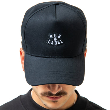 Person wearing a black cap with 'SUB LABEL' logo on a white background