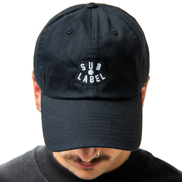 Black cap with 'SUB LABEL' logo worn by a person on a white background