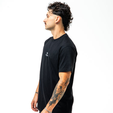 Man wearing a black t-shirt with a small logo on a white background