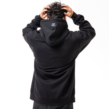 Person wearing a black hoodie with a logo on the back, standing against a white background