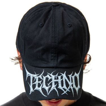 Black cap with white 'techno' logo worn by a person on a white background
