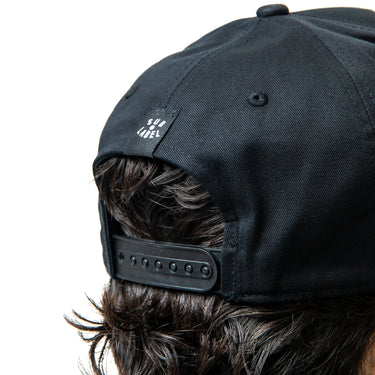 Black cap worn by a person on a white background