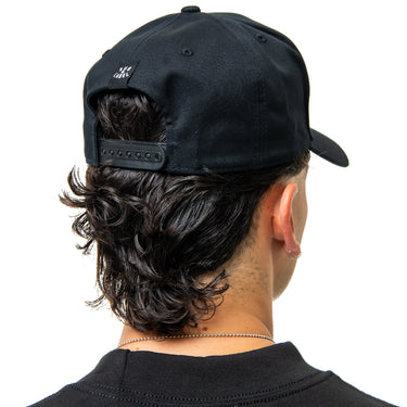 Person wearing a black cap with a small logo on the back, viewed from behind.