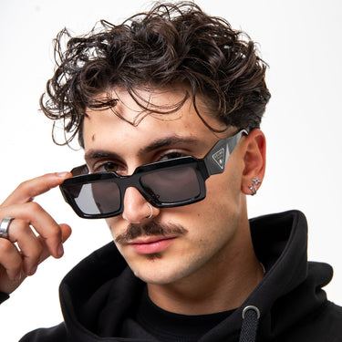 Man wearing sunglasses and a black hoodie against a white background