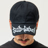 Person wearing a black cap with 'Sub Label' logo on a white background