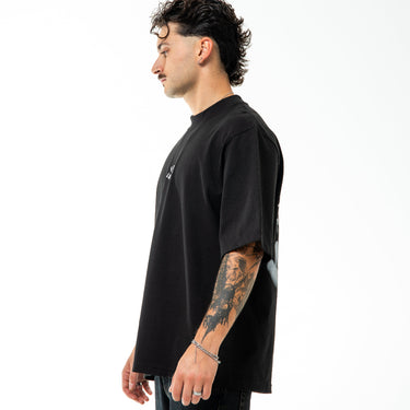 Person wearing a black t-shirt with a small white logo on a white background