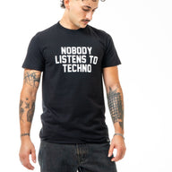 Person wearing a black t-shirt with 'Nobody Listens to Techno' text on a white background
