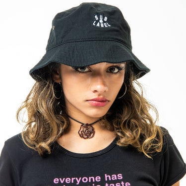 Girl wearing a black bucket hat and black t-shirt with text on a white background