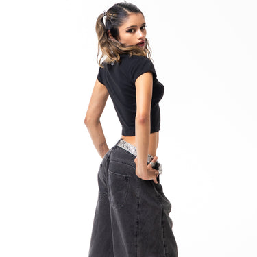 Woman wearing a black top and wide-leg jeans on a white background