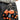 Two orange trolls keychains with black shirts on a person's belt.