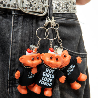 Two orange trolls keychains with black shirts on a person's belt.