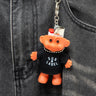 Orange troll keychain with 'Sub Label' on a black denim pocket