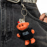 Person wearing a belt with a keychain shaped like a small orange creature in a black shirt.