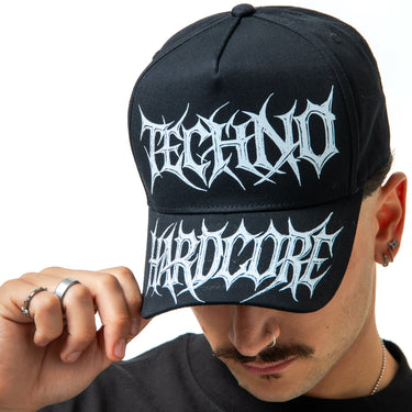 Person wearing a black cap with 'Techno Hardcore' text on a white background