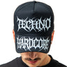 Person wearing a black cap with 'Techno Hardcore' text on a white background