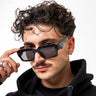 Man wearing sunglasses and a black hoodie against a white background